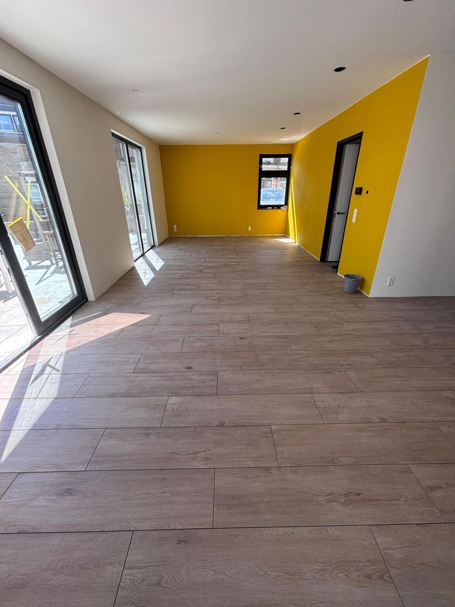 Woonkamer met houtlook vloertegels in visgraatverband en gele wand